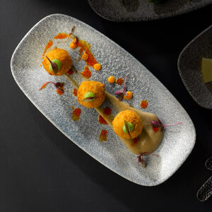 a light tapas dish on a grey sparkly Raku platter dish, positioned on a black table.