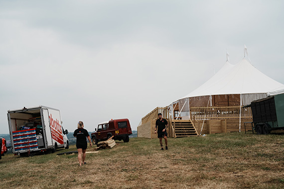Two Abbott's employees walking in a field with two vehicles visible to their left and a large marquee with wooden steps in the background.